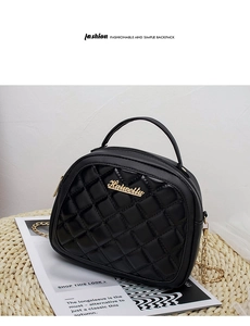 Detail of black quilted leather handbag with gold chain strap and metal logo