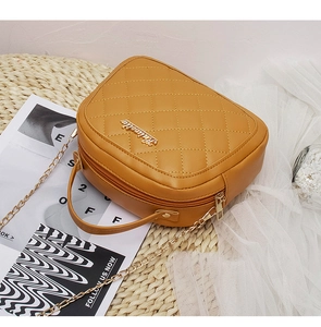 Close-up of mustard yellow quilted crossbody bag with gold chain and metal logo