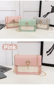 Détail du sac bandoulière bicolore avec pendentif couronne dorée et chaîne en métal doré
