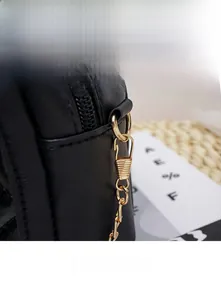 Detail of gold metal buckle and stitching on black leather crossbody bag for women