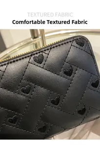 Detail of black quilted leather wallet featuring heart embroidery and gold zipper