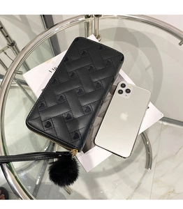 Detail of black quilted leather wallet with heart patterns and fuzzy pompom charm