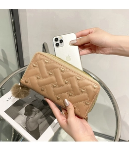 Brown long quilted wallet with heart embroidery next to iPhone for size comparison