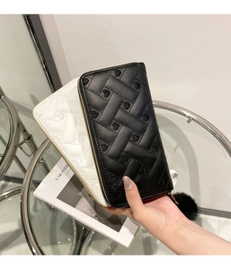 Detail of heart embroidered quilted leather wallet with gold zipper and fur ball charm