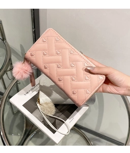 Detail of woven texture with heart embroidery and fluffy pom-pom charm on pink long wallet