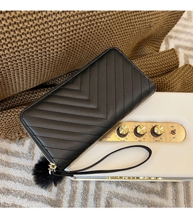 Detail of black chevron quilted long wallet with wrist strap and soft pompom charm