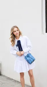 Light blue bucket bag with lychee texture worn by a model in a white dress