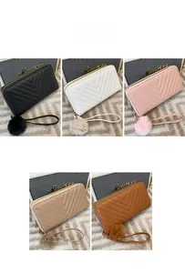 Detail view of chevron quilted wallets with detachable wristlets and fluffy pompom charms