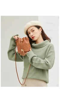 Detail of vintage brown bucket bag with embossed circular patterns and tassel drawstring