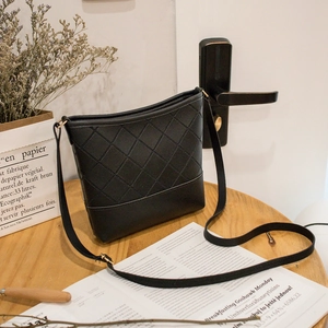 Sac seau matelassé noir avec bandoulière présenté dans un décor de style de vie