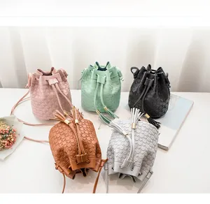 Detail of five mini bucket bags with embossed texture and tassel drawstrings