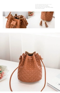 Close-up of embossed floral pattern and tassel details on a brown leather bucket bag