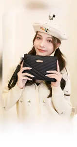 Detail of black V-quilted faux leather handbag with gold plaque and side wristlet strap