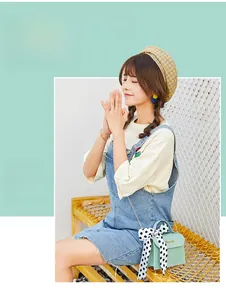 Detail of mint green shoulder bag featuring a polka dot scarf handle and gold chain strap