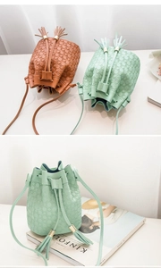 Detail of embossed bucket bag with drawstring closure and twin tassels in brown and mint green