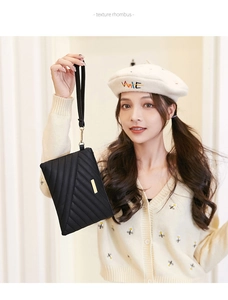 Detail of black quilted wristlet clutch with rhombus stitching and gold metal plate