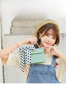 Mint green crossbody bag with golden chain and black polka dot scarf detail on strap