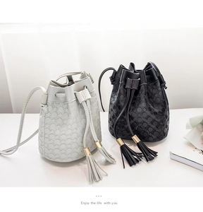 Detail of black and white drawstring bucket bags with textured wave pattern and tassels