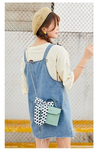 Detail of mint green crossbody bag featuring a large polka dot bow and gold chain strap