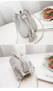 Detailed close-up of light grey bucket bag with textured dots and stylish dual tassels