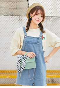 Detail of light green chain bag featuring a decorative polka dot scarf on the handle