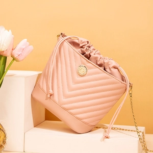 Close-up of pink chevron-quilted bucket bag with gold chain and drawstring detail