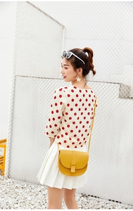 Detailed side view of a yellow mini saddle bag with flip cover on a crossbody strap