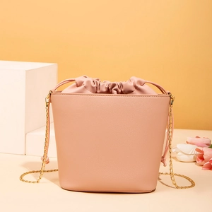 Detail of pink bucket bag with drawstring liner and elegant gold chain strap