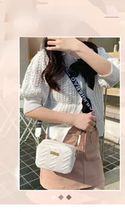 Close-up of white quilted crossbody bag with stylish patterned strap and gold hardware