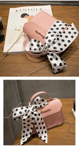 Detail of pink chain handbag with silk scarf handle on wooden table near Kinfolk magazine