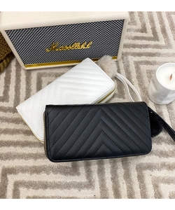 Close-up of quilted long wallets with chevron stitching, gold zippers and pom pom charms