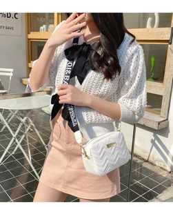 Macro detail of white V-quilted faux leather bag with stylish printed wide shoulder strap