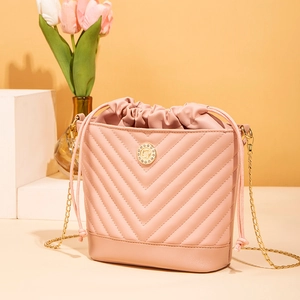 Detail view of pink chevron quilted bucket bag with rhinestone logo and gold chain strap