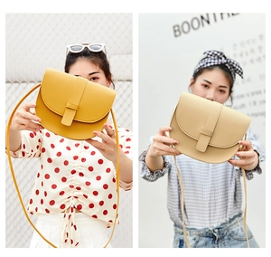 Detail shot of yellow and beige saddle bags with stitching and decorative buckles