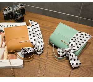 Detail of square leather shoulder bags in mustard yellow and green with polka dot bows