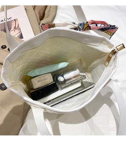Detailed interior of a white quilted tote bag showing large capacity and zipper closure