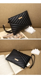 Close-up of black quilted PU leather clutch with gold metal decor and wristlet strap