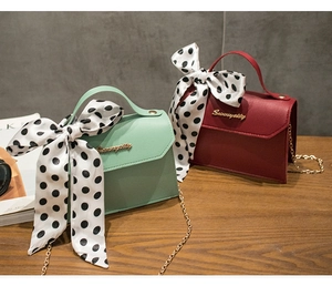Detail of elegant chain bags in mint green and burgundy with silk polka dot scarves