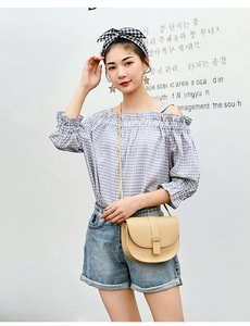Street style shot of a beige saddle crossbody bag with a blue checkered blouse