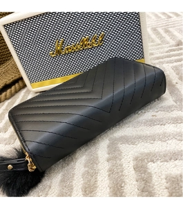 Close-up of black chevron quilted long wallet with soft faux fur pompom charm