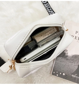 Interior view showing capacity of white quilted crossbody camera bag with printed strap