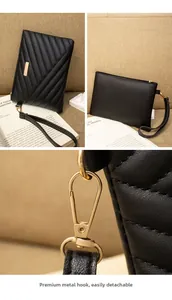 Detail of black quilted leather clutch set with detachable gold metal hook and zipper