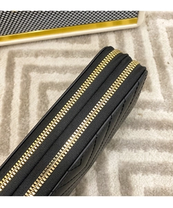 Detail of black quilted leather wallet with gold double zippers and V-shaped stitching