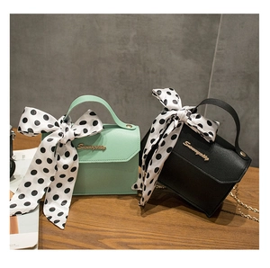 Detail of mint green and black chain bags featuring large polka dot ribbon bows