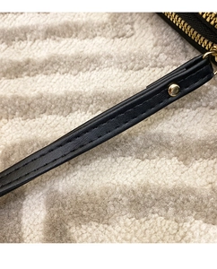 Detail of black leather wallet with V-stitch embroidery and golden metal rivets