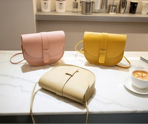 Chic saddle crossbody bags in pink, yellow, and beige on a marble surface backdrop