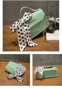 Detail view of mint green crossbody bag with polka dot bow and gold chain strap