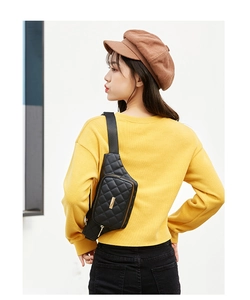 Detail of black quilted crossbody chest bag with gold metal trim and diamond stitching