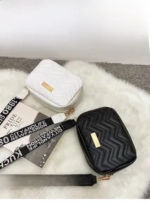 Detail view of V-quilted mini crossbody bags in black and white with wide logo strap