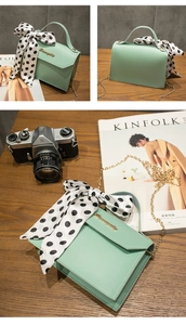 Detail of mint green chain bag with wave logo, decorative silk scarf and metal chain